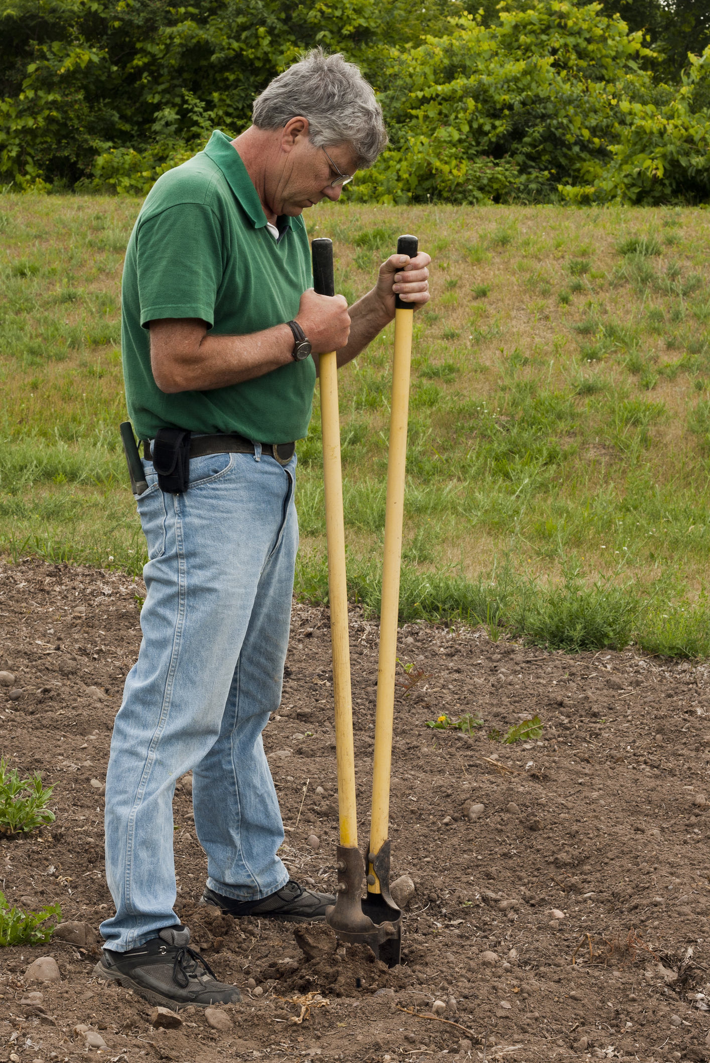 Man preparing to erect a fence by digging a post hole