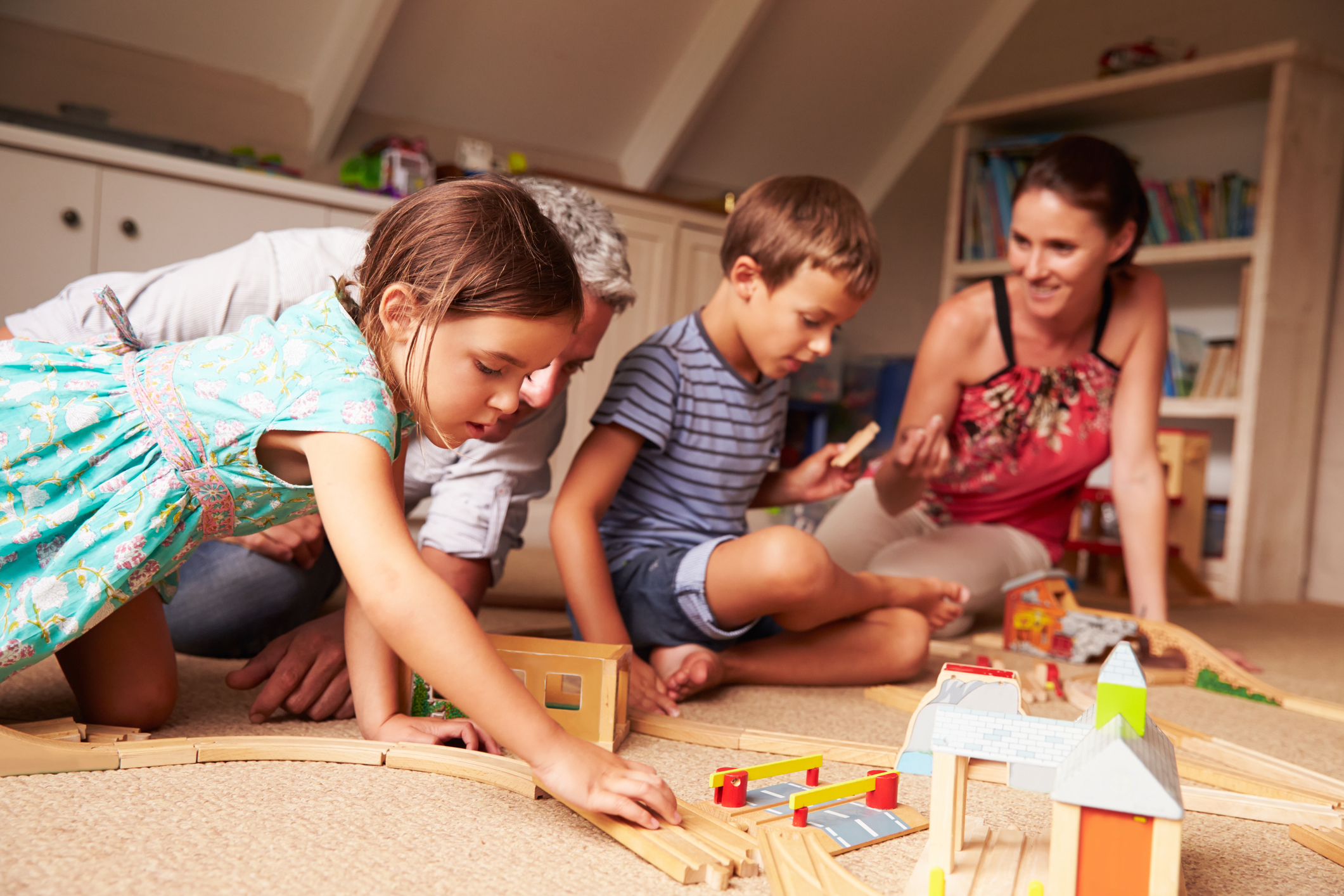 Parents playing with kids and toys in an attic playroom