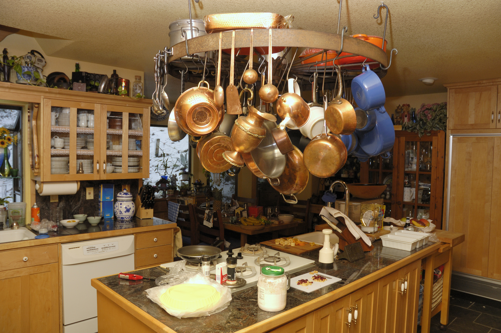 A well used kitchen with pots and pans hanging from wheel over island